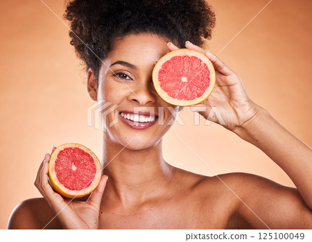 Grapefruit, skincare and portrait of black woman with a beauty, organic and natural routine. Cosmetics, citrus fruit and African model with cosmetic facial treatment in studio with orange background. Grapefruit, skincare and portrait of black woman with a beauty, organic and natural routine. Cosmetics, citrus fruit and African model with cosmetic facial treatment in studio with orange background. 125100049