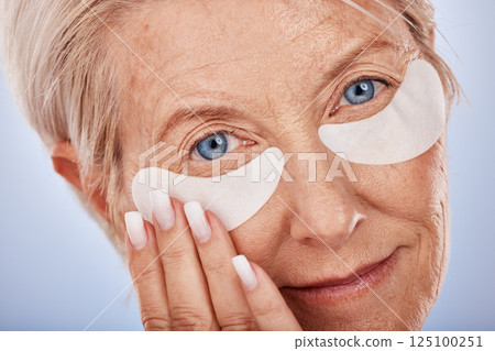 Face, beauty and eye mask with a senior woman in studio on a gray background for antiaging treatment. Portrait, cosmetics and wrinkles with a mature female posing to promote a natural product Face, beauty and eye mask with a senior woman in studio on a gray background for antiaging treatment. Portrait, cosmetics and wrinkles with a mature female posing to promote a natural product 125100251