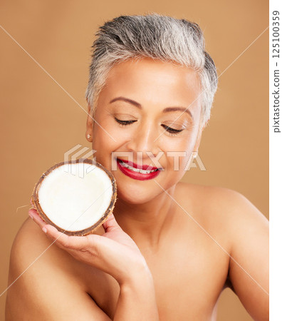 Beauty, coconut and skincare with woman in natural cosmetic product advertising against studio background. Healthy skin, fresh and clean with organic cosmetics, face and body care for antiaging. 125100359