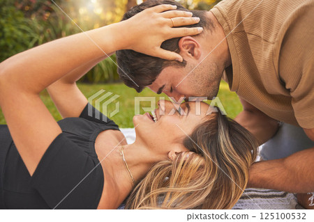 Love, park and couple kiss on picnic date to show affection, bonding and romance. Relationship, dating and young man kissing head of woman sitting on blanket, enjoying weekend, holiday and nature 125100532