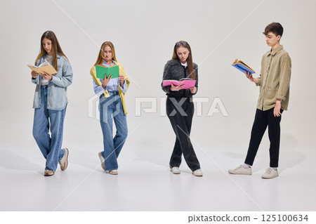 Four students standing in line reading books with focus and concentration, preparing for exams, expressing different academic emotions Four students standing in line reading books with focus and concentration, preparing for exams, expressing different academic emotions 125100634