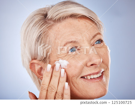 Skincare, thinking and senior woman with cream for face against a grey studio background. Sunscreen, happy and elderly model with an idea with a facial dermatology product for beauty and self care 125100725