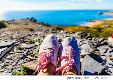 Female legs in sneakers against coast landscape, Spain. Female legs in sneakers against coast landscape, Spain. 125100880
