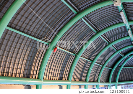 Arched roof made from metal sheet of Pedestrian pathway or corridor or hallway between train station and other building. Arched roof made from metal sheet of Pedestrian pathway or corridor or hallway between train station and other building. 125100951