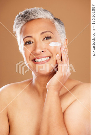 Facial, cream and mature woman, skincare lotion and sunscreen, beauty and anti aging dermatology product on studio background. Portrait senior lady, face cream and cosmetics, aesthetic glow and shine 125101097