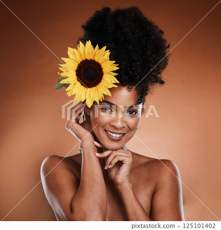 Beauty, skincare and black woman with flower in hair, portrait of happy lady with salon afro hairstyle, and smile on face. Nature, natural organic skin and haircare product for woman with sunflower. Beauty, skincare and black woman with flower in hair, portrait of happy lady with salon afro hairstyle, and smile on face. Nature, natural organic skin and haircare product for woman with sunflower. 125101402