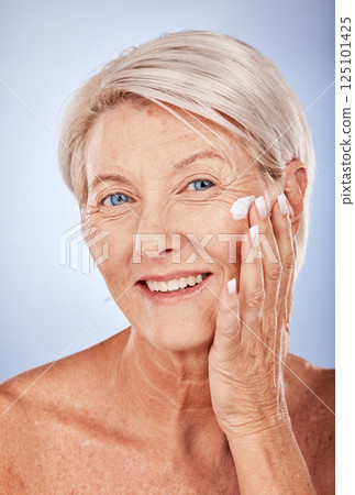 Portrait, skincare and senior woman with face cream for moisturizing on blue studio background. Beauty, smile or elderly female model apply facial creme, cosmetics product or lotion for healthy skin Portrait, skincare and senior woman with face cream for moisturizing on blue studio background. Beauty, smile or elderly female model apply facial creme, cosmetics product or lotion for healthy skin 125101425