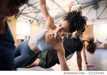 Fitness, active and healthy friends stretching, exercising or cardio training together in gym. Young fit people doing a full body workout exercise or warm up routine in the health and wellness club Fitness, active and healthy friends stretching, exercising or cardio training together in gym. Young fit people doing a full body workout exercise or warm up routine in the health and wellness club 125101442