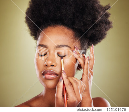 Black woman, eyeshadow makeup and brush in studio on green background. Skincare, self care and young female model holding makeup brush, cosmetics or eyeliner product for beauty aesthetics or wellness 125101676