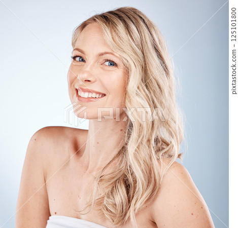 Hair care, cosmetics and portrait of a woman with healthy, happy and blonde hair on a grey studio background. Salon, smile and face of a young model with beauty, shine and clean hair from hairdresser 125101800