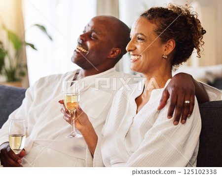 Black couple, champagne and spa therapy on a couch to relax, celebrate and feel zen while together at a hotel for hospitality. Man and woman, happy while drinking alcohol and enjoying quality time 125102338