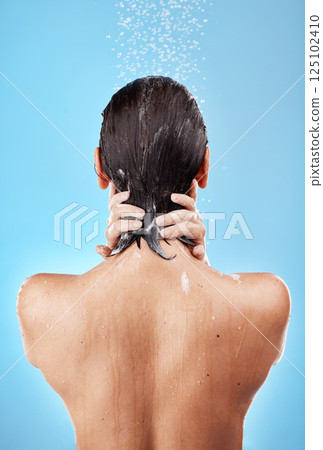 Back, shower and woman hygiene, wellness and body care for health, skincare and against blue studio background. Clean, female and girl wet, natural beauty and water splash to relax and washing. 125102410
