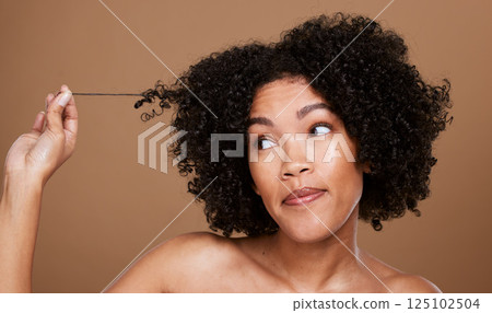 Black woman afro, messy hair and curls looking for cosmetics or salon treatment against a brown studio background. African American female in hair care holding entangled strand on mockup 125102504