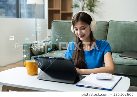 Smiling young woman in headphones taking notes, motivated interested student studying online.Smiling young woman in headphones taking notes, motivated interested student studying online. 125102605