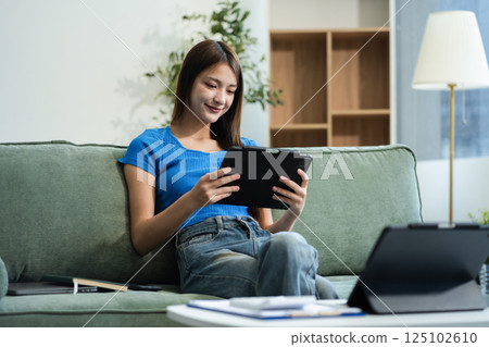 Happy woman entrepreneur working online at home office. Using a laptop for business, searching, and multitasking in a modern digital workspace. 125102610