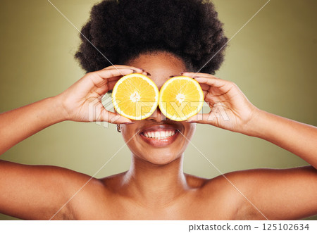 Skincare, beauty and happy woman with lemon in a studio for a natural, healthy and organic face routine. Cosmetics, citrus fruit and black model with a smile for facial treatment by green background. 125102634