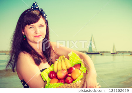 Woman holding picnic basket with fruits 125102659