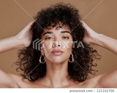 Hair care, black woman and portrait with curly hair, beauty and wellness by cosmetics background. Hair, model and jewelry earrings with cosmetic skin glow with makeup, gold jewellery and radiant face 125102700