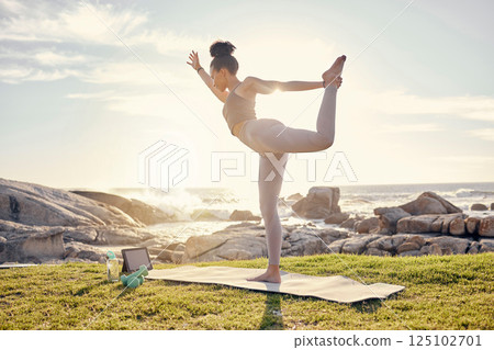 Yoga, training and woman with tablet at the beach with instructions from online fitness video. Wellness, nature and black woman in stretching exercise on yoga mat with workout tutorial by ocean 125102701