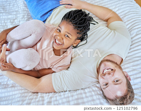 Family, portrait and smile while on bed to relax, love and trust after adoption with father and foster child in home bedroom for quality time. Man and girl from top while bonding, happy and together 125102796