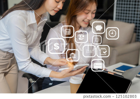 Business team analyzing documents, graphs, and data with a laptop, tablet, and smartphone. Collaboration, strategy, and success in a modern office. 125102803