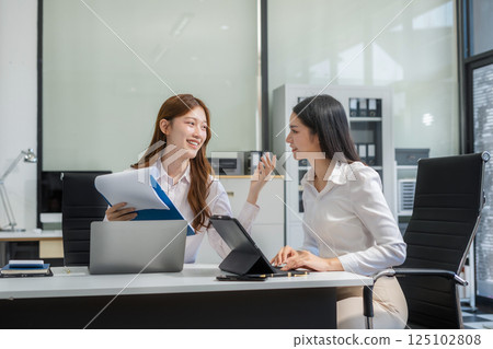 Business team analyzing documents, graphs, and data with a laptop, tablet, and smartphone. Collaboration, strategy, and success in a modern office. 125102808