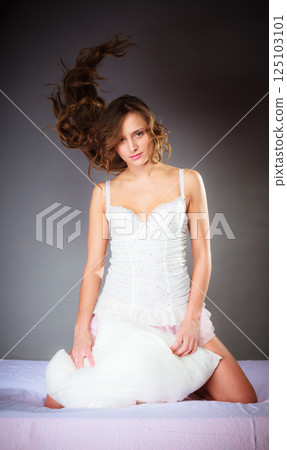Woman on bed with pillow and wind in hair. Woman on bed with pillow and wind in hair. 125103101