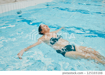 Relax, wellness and woman swimming in water at retirement home calm, peaceful and floating. Health, fitness and peace of senior swimmer in pool with happy smile excited for exercise break. Relax, wellness and woman swimming in water at retirement home calm, peaceful and floating. Health, fitness and peace of senior swimmer in pool with happy smile excited for exercise break. 125103108