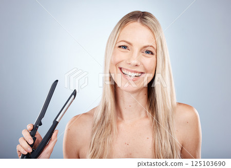 Portrait, hair care and woman with flat iron, natural beauty and treatment for wellness against grey studio background. Young female, girl and with salon equipment for scalp treatment, care and smile 125103690