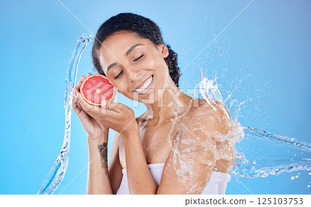 Shower, water and grapefruit with a model black woman in studio on a blue background with a splash for hygiene. Health, water splash and skincare with an attractive young female holding natural fruit 125103753