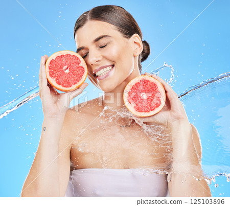 Woman, water splash or healthy grapefruit in skincare grooming, vitamin c treatment or dermatology on blue background studio. Beauty model, smile or fresh citrus food for organic hydration wellness Woman, water splash or healthy grapefruit in skincare grooming, vitamin c treatment or dermatology on blue background studio. Beauty model, smile or fresh citrus food for organic hydration wellness 125103896