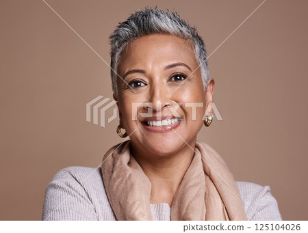 Face, fashion and senior woman in studio isolated against a brown background. Beauty portrait, smile and makeup cosmetics or aesthetics of happy elderly model from India in designer scarf or clothes. 125104026