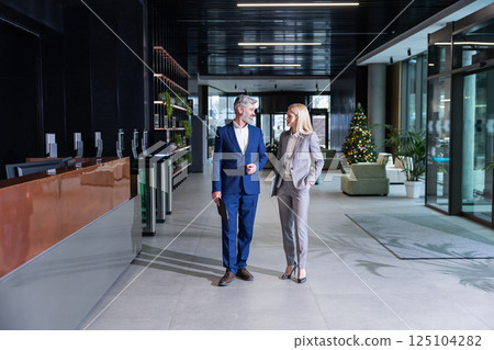 Businesspeople standing in corridor smiling while discussing corporate solutions 125104282