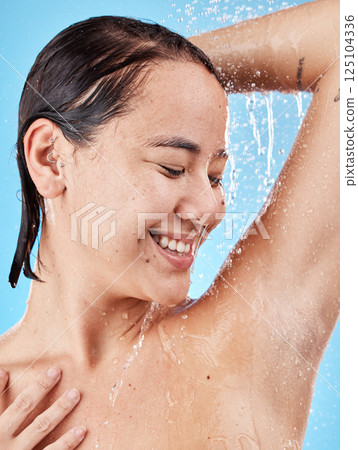 Skincare, cleaning and woman in shower in studio isolated on a blue background. Water splash, hygiene and healthy female model from Canada bathing and washing for beauty, body care and wellness. 125104336