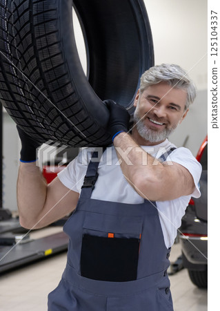 Mechanic holding tire tire at repair garage doing replacement of tires 125104337