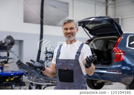 Man in uniform working indoors in garage Man in uniform working indoors in garage 125104380