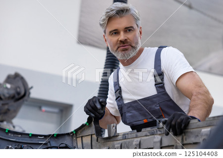 Male mechanic in uniform using tool in garage checking automobile for repair Male mechanic in uniform using tool in garage checking automobile for repair 125104408