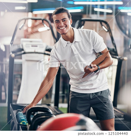 Training, portrait and fitness coach doing inspection of equipment at the gym. Wellness, sport and happy trainer doing check, planning and working at a club for athlete health, sports and workout 125104440