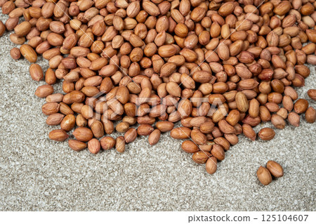 Pile of unpeeled brown raw peanuts on a gray background Pile of unpeeled brown raw peanuts on a gray background 125104607