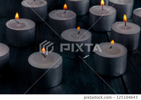 Tea light candles on a dark background, many lights in the dark 125104643