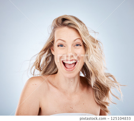 Woman, excited face or expression and blonde hair in motion on gray studio background in frizz free wavy hairstyle. Portrait, happy smile or wow beauty model and healthy hair care or grooming routine 125104833