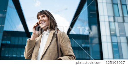 Business woman, phone call and smile for communication, networking and conversation with contact or investor outdoor by office buildings. Happy entrepreneur with smartphone with 5g network connection 125105027