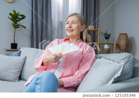 Mid aged woman in pink shirt with a fan in hands 125105346