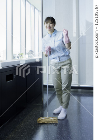 一位年輕女清潔工擦拭浴室地板的全身畫像。照片由電波學園東京電子專門學校提供。 125105367