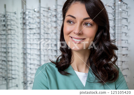 Dark-haired young female ophthalmologist in a optic shop Dark-haired young female ophthalmologist in a optic shop 125105420