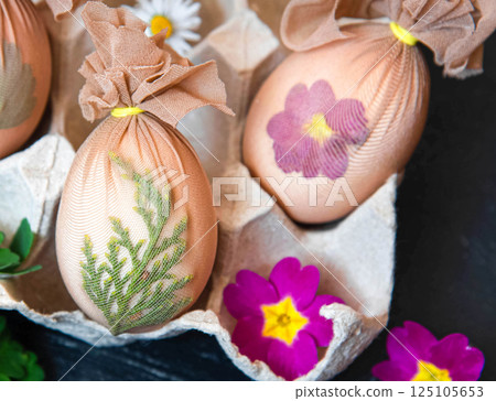 Preparing Easter eggs before painting with a pattern of fresh herbs, flowers 125105653