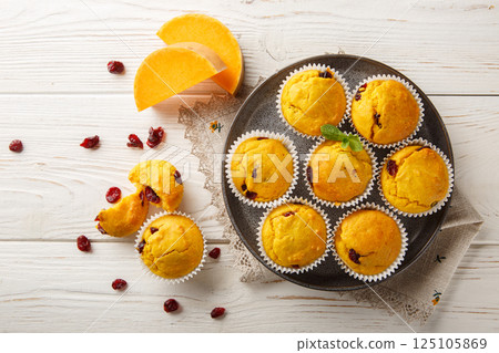 Freshly baked pumpkin muffins with dried cranberries, orange zest and spices close-up in a plate. Horizontal top view 125105869