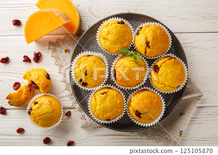 Autumn muffins with pumpkin puree, dried cranberries, orange zest and spices close-up in a plate. Horizontal top view 125105870