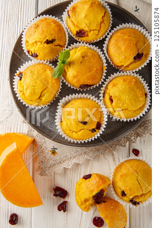 Delicious pumpkin cranberry muffins are made with pumpkin puree and dried cranberries closeup on the plate. Vertical top view 125105874