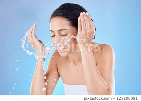 Water, splash and skincare woman in studio for face cleaning, morning wellness and healthy glow with blue background for advertising space. Beauty model with water in hands for facial cosmetic wash 125106081